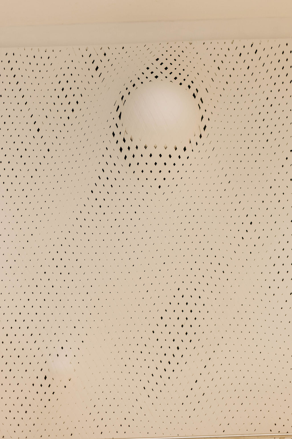Uma das esferas emergindo da trama de elástico branco, vista de frente